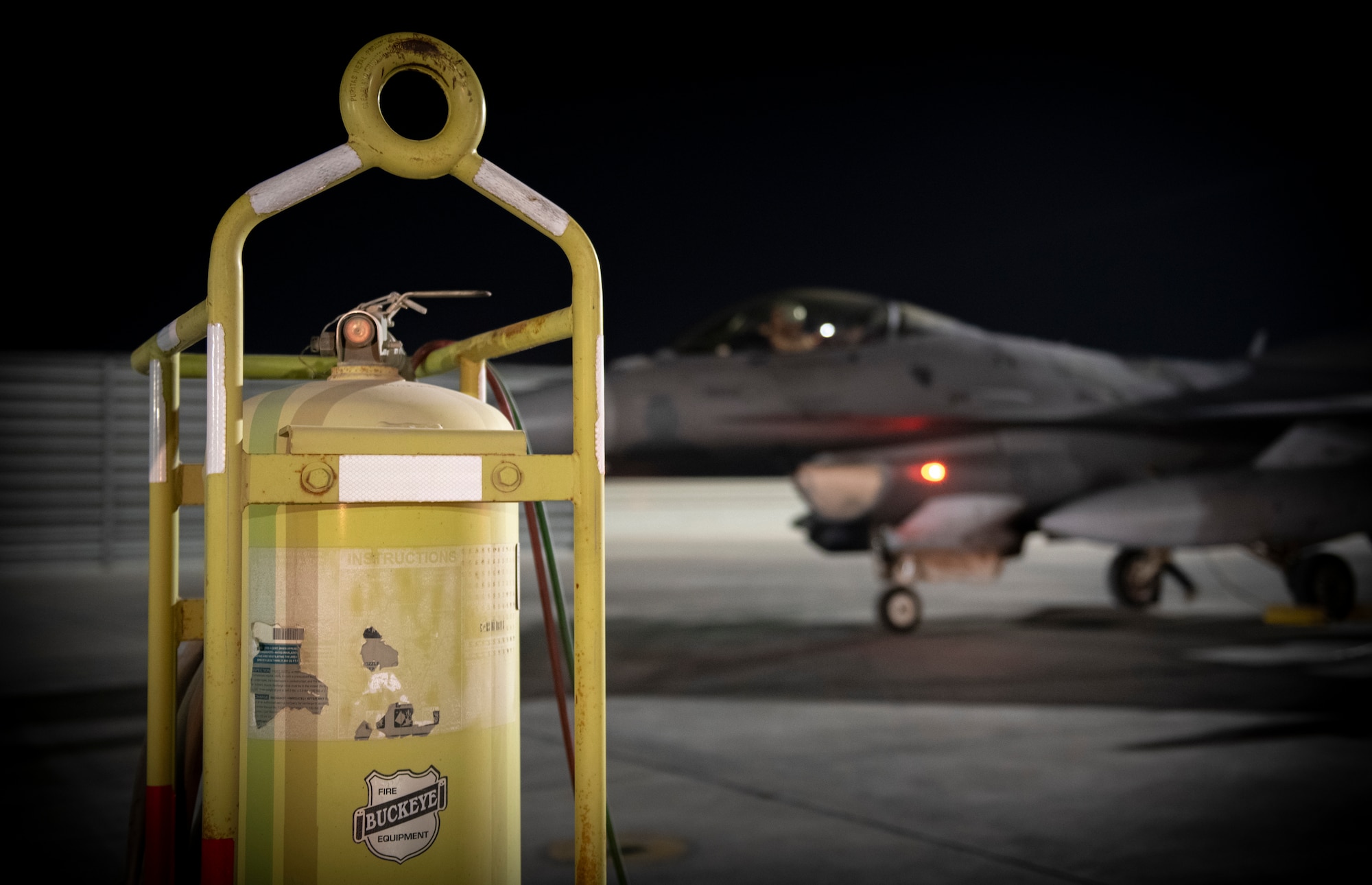 Military jet drives behine flight line fire extinguisher.