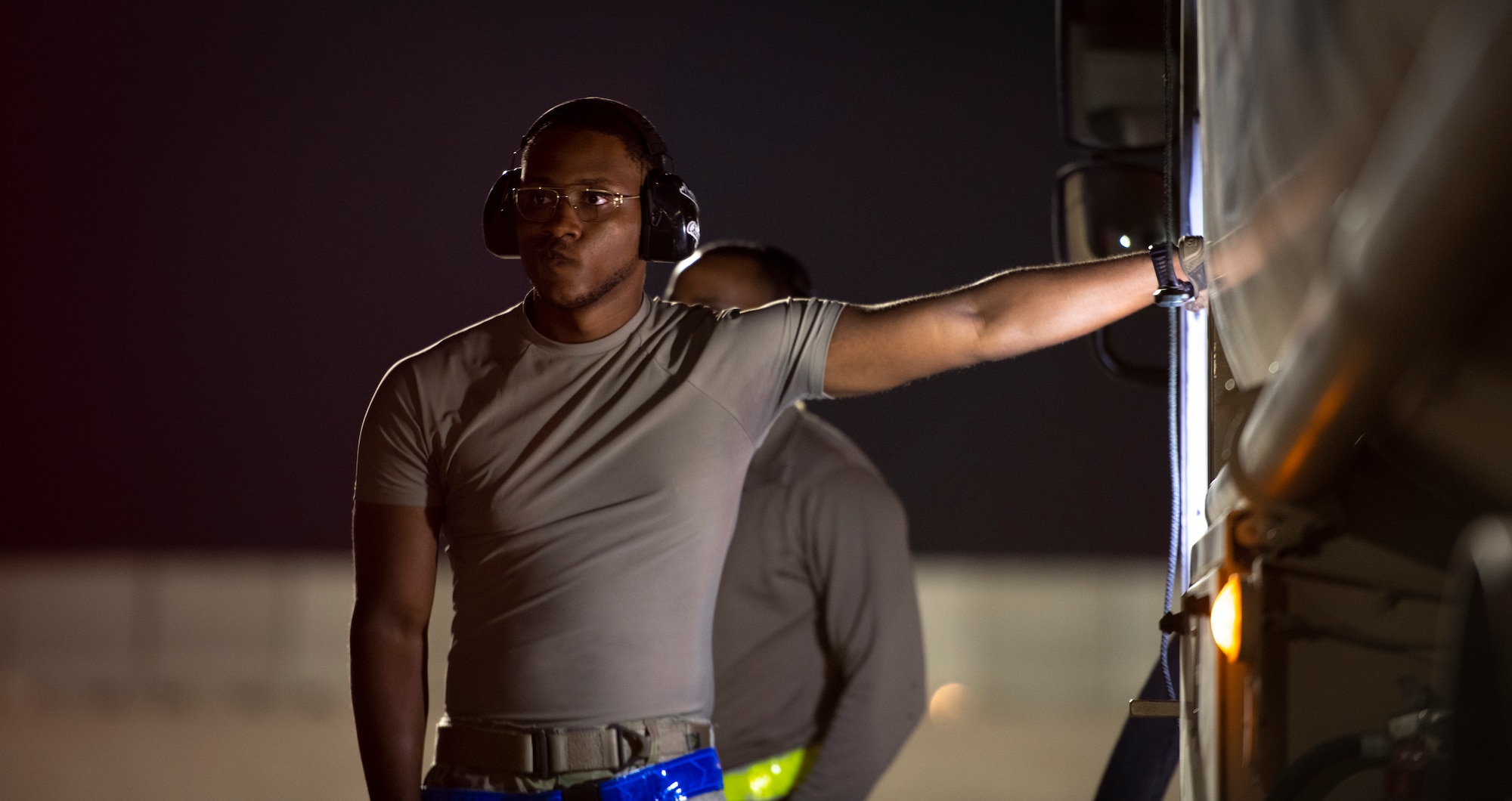 Military member leans up against fuel truck