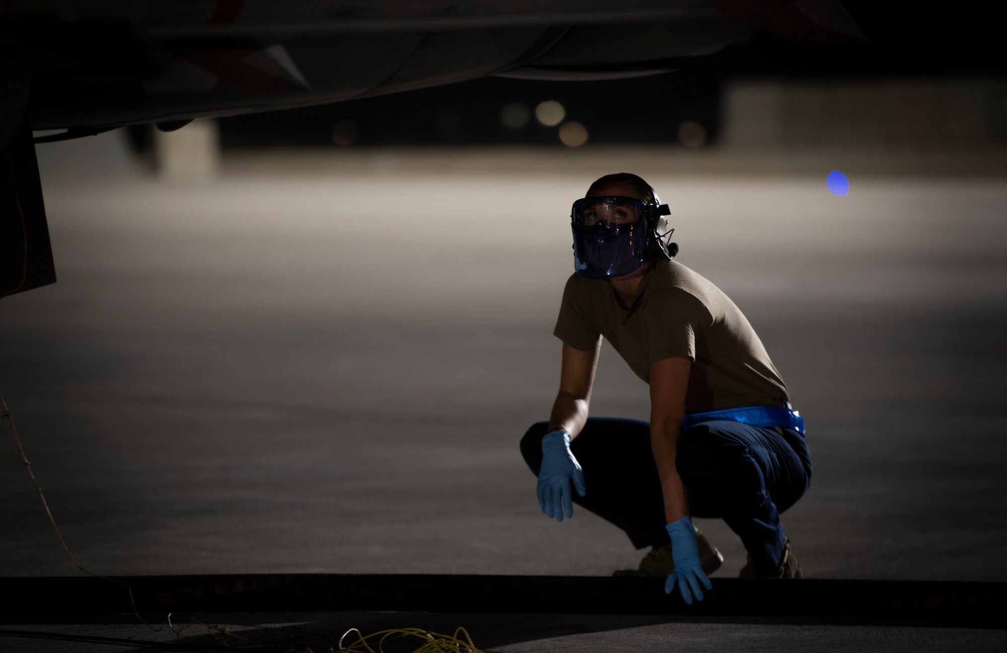 Military member looks up at plane during refueling.