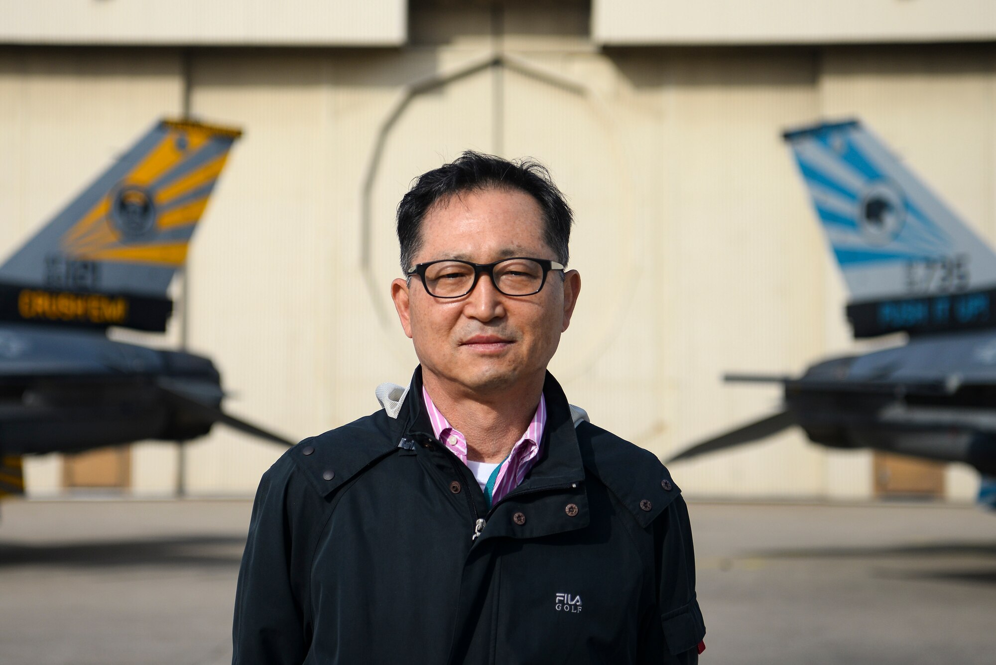 A Korean civilian stands in front of two fighter jets.