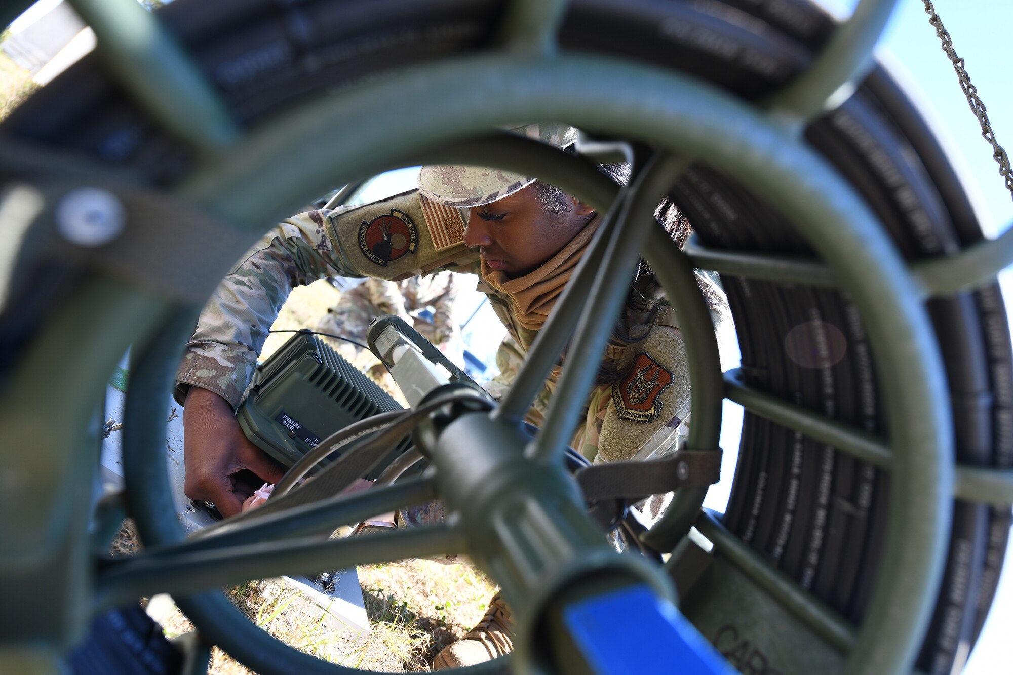 A cyber technician kneels behind a high frequency whip antenna