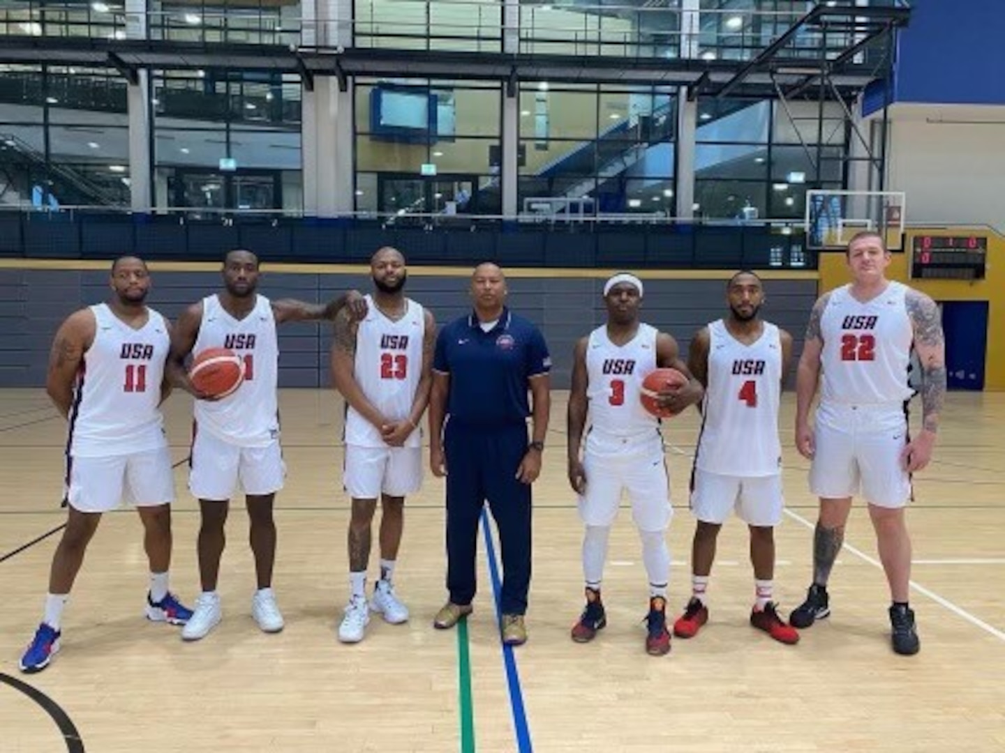U.S. Coast Guard Cmdr. Micah Bonner, Director of Auxiliary Southern Region for the First Coast Guard District and head coach of the USA Armed Forces Men’s Basketball Team, poses with members of the team before playing in the Supreme Headquarters Allied Powers Europe (SHAPE) International Basketball Tournament (IBT) in Mons, Belgium, November 2021. The annual tournament brings teams from around the world together to a NATO installation for friendly competition and partnership. (U.S. Coast Guard courtesy photo)