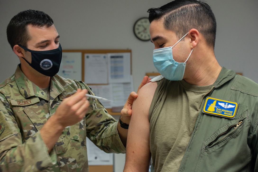 An airman vaccinates another airman.