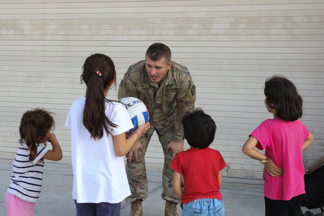 A soldier talks to four Afghan children.