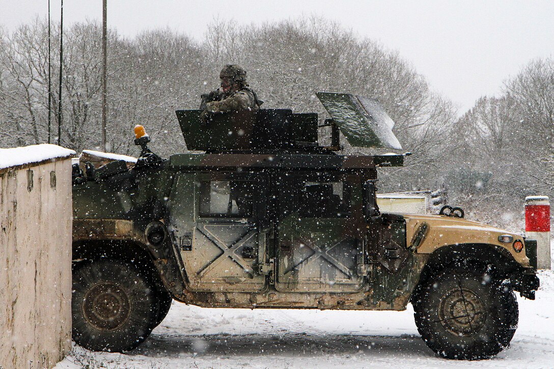Soldiers ride in a military vehicle as snow falls.