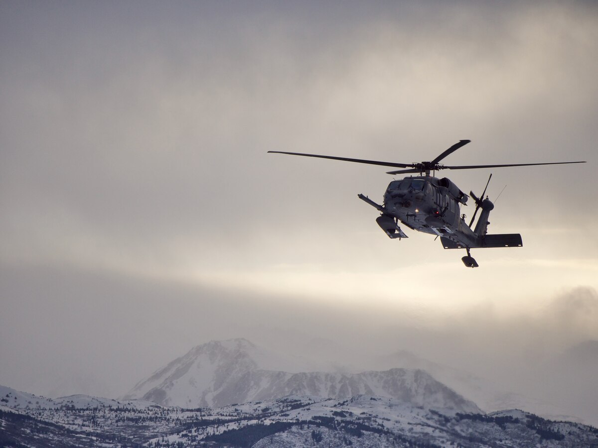 An Alaska Air National Guard 210th Rescue Squadron HH-60G Pave Hawk transits Joint Base Elmendorf-Richardson's Malamute Drop Zone Feb. 10, 2021, during parachute jump operations. The jump preceded the change-of-command ceremony for 212th Rescue Squadron. (U.S. Air National Guard photo by David Bedard/Released)