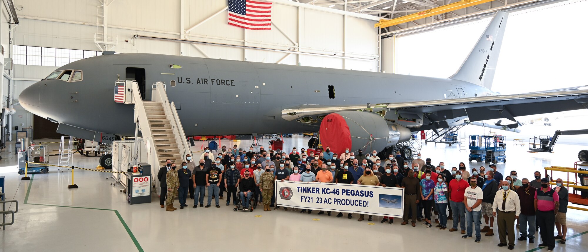 Group photo of people in front of aircraft in hangar