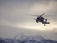 An Alaska Air National Guard 210th Rescue Squadron HH-60G Pave Hawk transits Joint Base Elmendorf-Richardson's Malamute Drop Zone Feb. 10, 2021, during parachute jump operations. The jump preceded the change-of-command ceremony for 212th Rescue Squadron. (U.S. Air National Guard photo by David Bedard/Released)