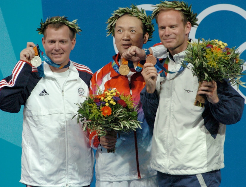 Olympic medalists pose together while holding their medals.