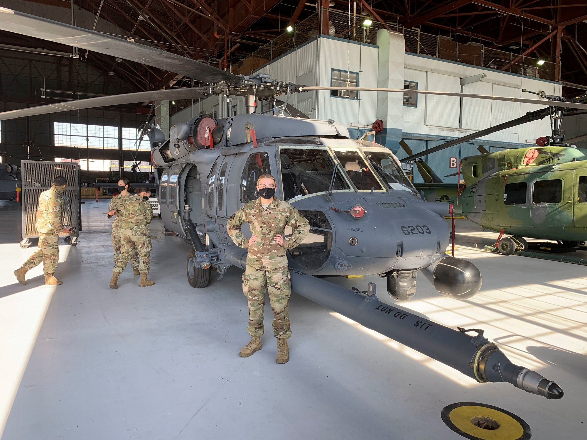 Senior Airman Selina Fuller, center, 68th Rescue Squadron rescue intelligence analyst, poses for a photo in front of an HH-60 Pave Hawk at Davis-Monthan Air Force Base, Arizona.
