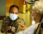 Pvt. Nastasia Morgan, a combat medic assigned to the 107th Military Police Company, 369th Sustainment Brigade, sits with a resident at Loretto Health and Rehab in Syracuse, NY Dec. 20.