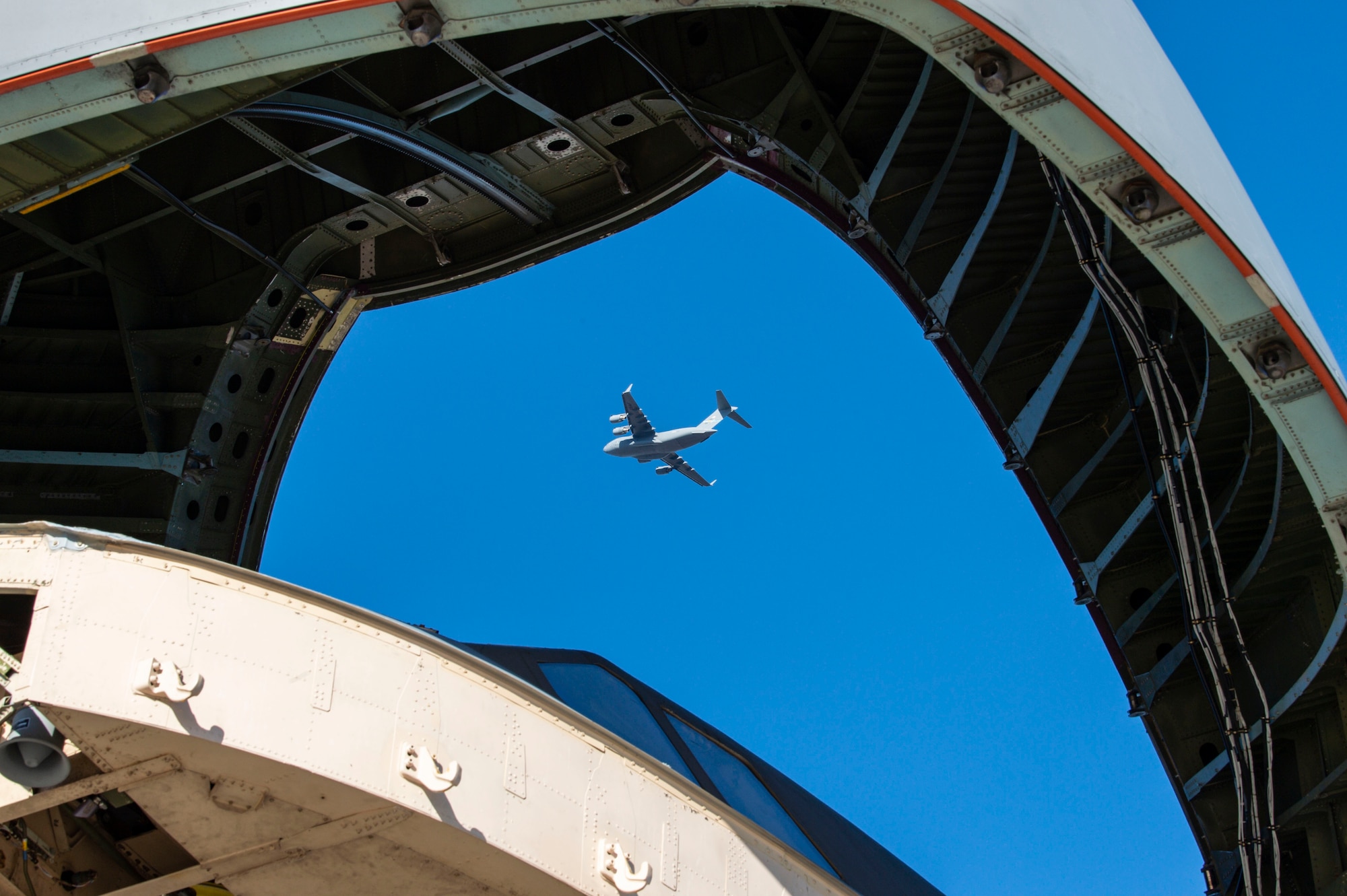 Looking through the open visor of a C-5M Super Galaxy, a C-17 Globemaster III flies overhead after completing a touch and go landing during a local training flight at Dover Air Force Base, Delaware, Dec. 20, 2021. Thirteen C-17s are assigned to Dover AFB, along with 18 C-5Ms that provide 20 percent of the nation's outsized airlift capacity. (U.S. Air Force photo by Roland Balik)