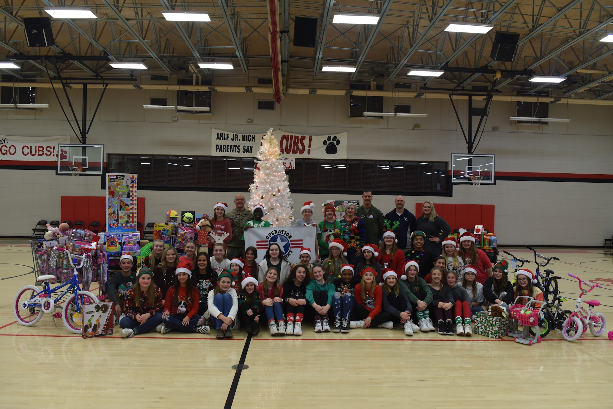 189th Airlift Wing leadership, Ahlf Junior High School faculty and students pose for a group photo with toy donations on behalf of the school and Operation Homefront, Dec. 8, 2021, in Searcy, Ark. The donation drive was coordinated through the school with the 189 AW Airman and Family Readiness office and toys were given to Team Little Rock families. (U.S. Air National Guard photo by Master Sgt. Jessica Roles)