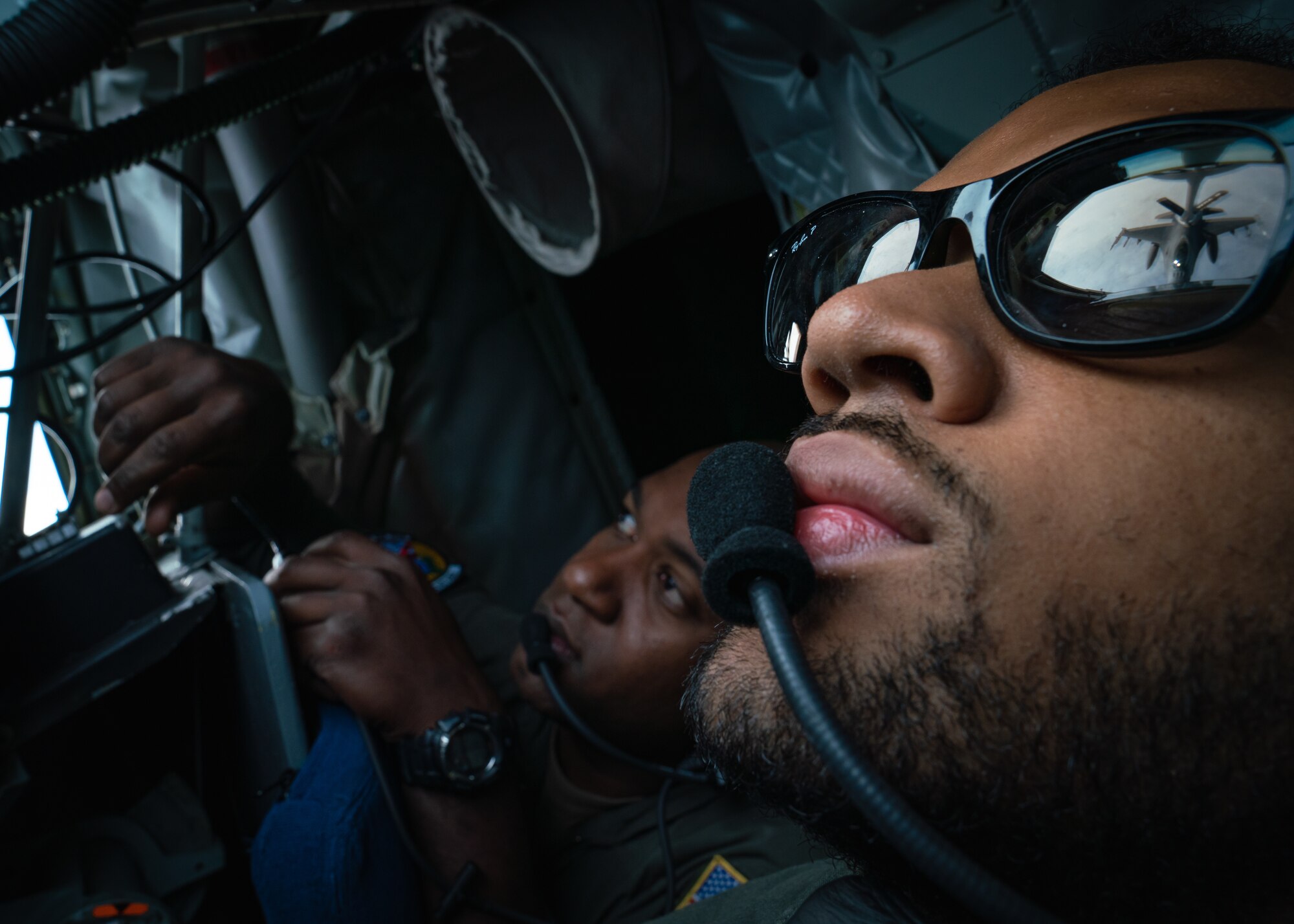 U.S. Air Force Staff Sgt. Kevin Satberry, 91st Air Refueling Squadron instructor boom operator, left, evaluates Senior Airman Caleb Mills, 91st ARS boom operator, right, during a refueling exercise over Alabama, Dec. 21, 2021.