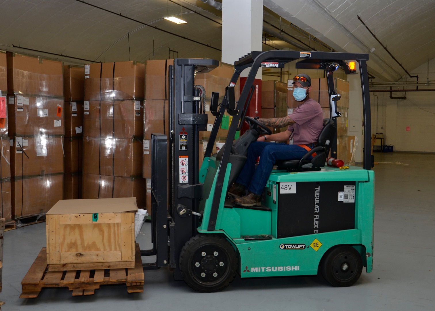 A man operates a forklift inside a warehouse.