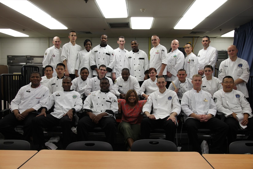 A woman poses with culinary school students.
