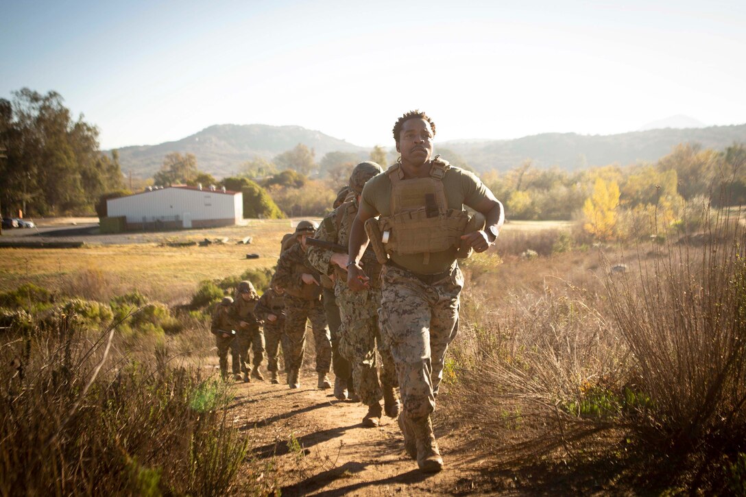 Sailors run in a line in a field.