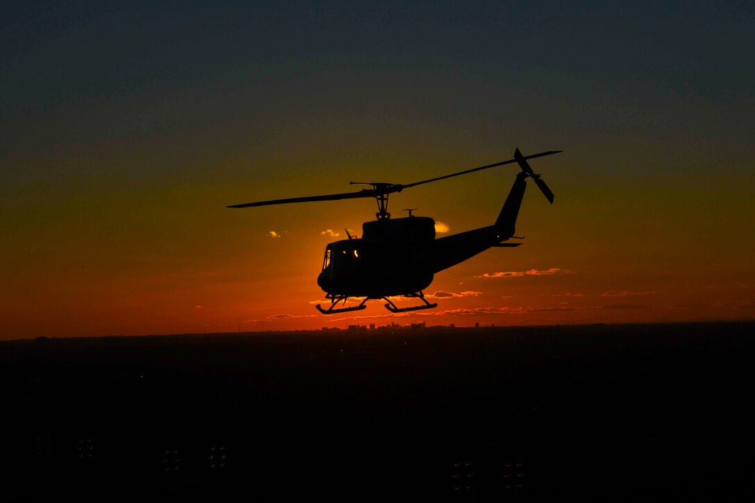 An airborne helicopter shown in silhouette.