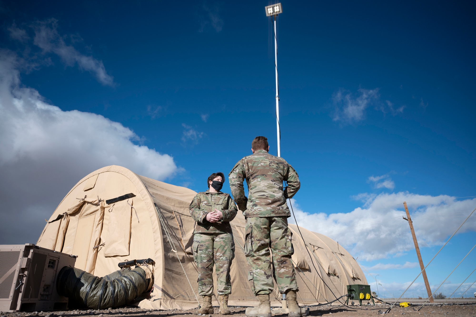 Col. Nicole Fuller, 635th Supply Chain Operations Wing vice commander, discusses expeditionary lighting systems with Senior Airman Brandon Pophal, 635th Materiel Maintenance Group electrical systems journeyman, during a familiarization tour at the Basic Expeditionary Airfield Resources (BEAR) Base, Dec. 10, 2021, on Holloman Air Force Base, N.M. Emergency airfield lighting systems (EALS) and rapid area lighting systems (RALS) are easily deployable lighting systems that can be used in any environment. (U.S. Air Force photo by Airman 1st Class Antonio Salfran)