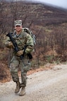 Spc. Jorday Cornett, a Soldier with the Recruiting and Retention Battalion, carries his rucksack  during a timed ruck march during the Best Warrior Competition on Camp Williams, Utah
