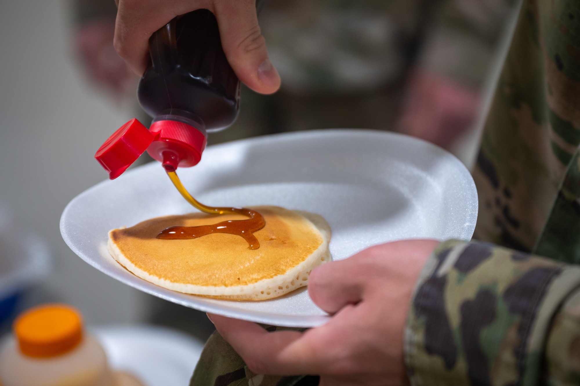 A dorm resident pours syrup on his pancake during the “Storm the Dorm” event