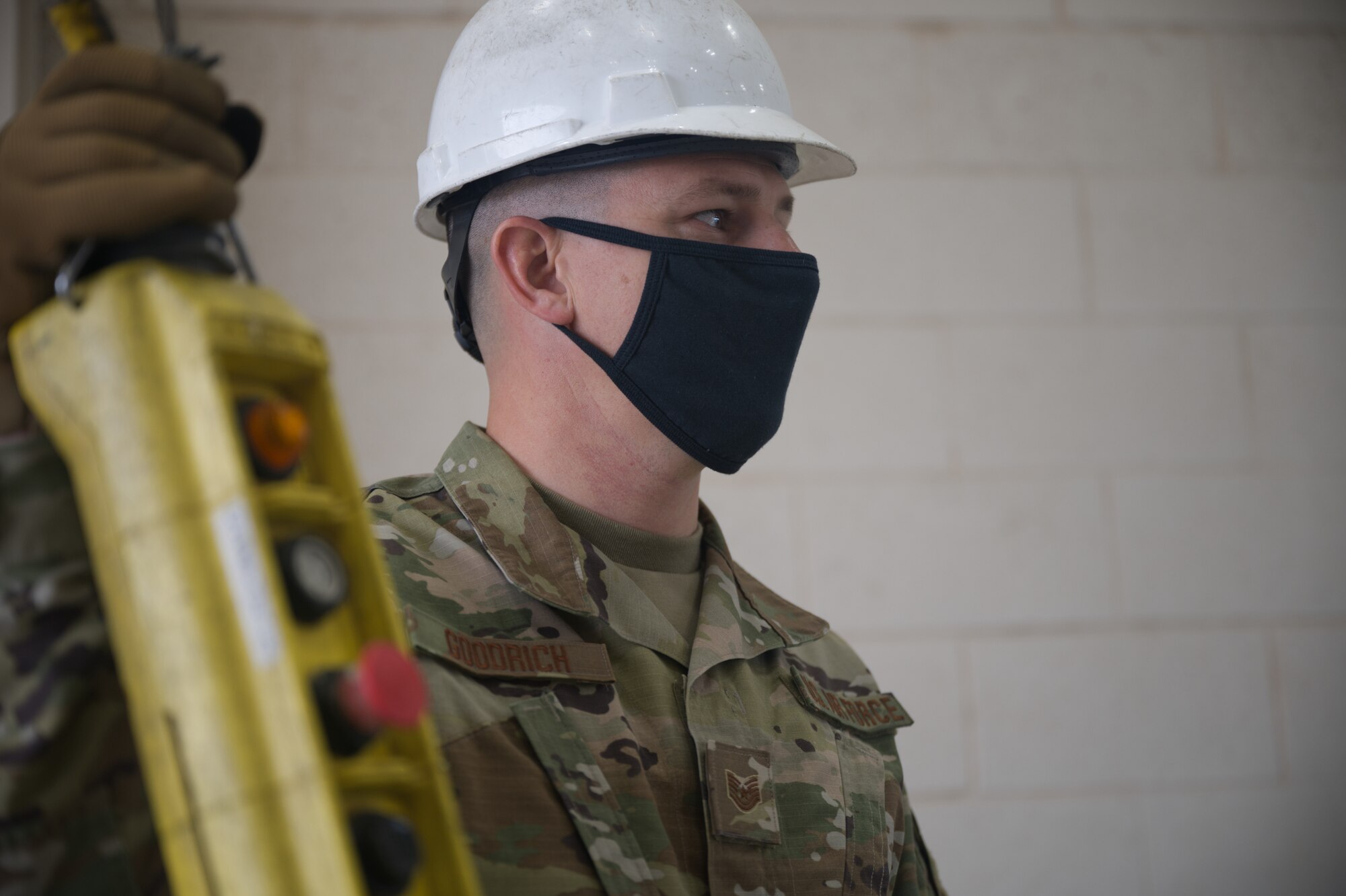 An Airman holds the the operating mechanism of an electric hoist.