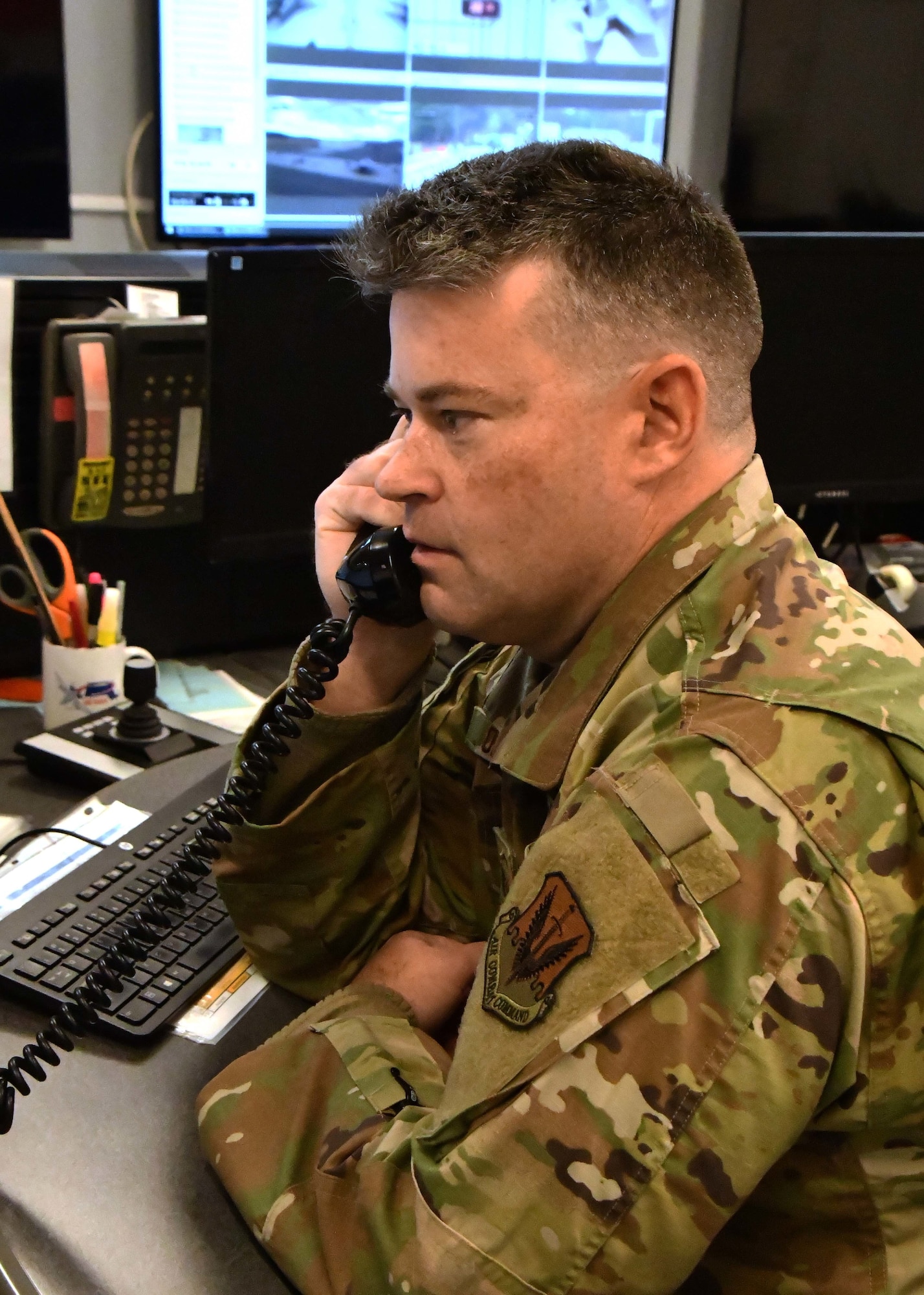 Master Sgt. Robert Ollquist, 104th Fighter Wing command post Non-commissioned Officer in Charge, answers a phone December 3, 2021, at Barnes Air National Guard Base, Massachusetts. The command post is responsible for receiving and dispersing all information coming onto or leaving Barnes ANGB.  (U.S. Air National Guard photo by Staff Sgt. Sara Kolinski)