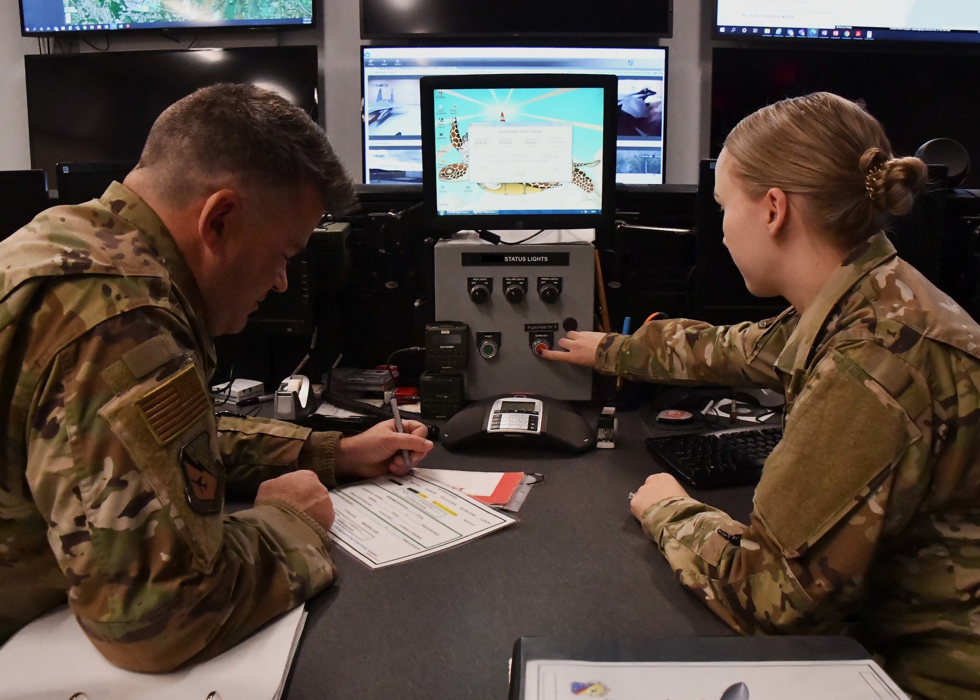 Master Sgt. Robert Ollquist, 104th Fighter Wing command post Non-commissioned Officer in Charge, and Staff Sgt. Chelsey Potter, 104th Fighter Wing command post controller, execute mission requirements December 3, 2021, at Barnes Air National Guard Base, Massachusetts. The command post is responsible for receiving and dispersing all information coming onto or leaving Barnes ANGB.  (U.S. Air National Guard photo by Staff Sgt. Sara Kolinski)