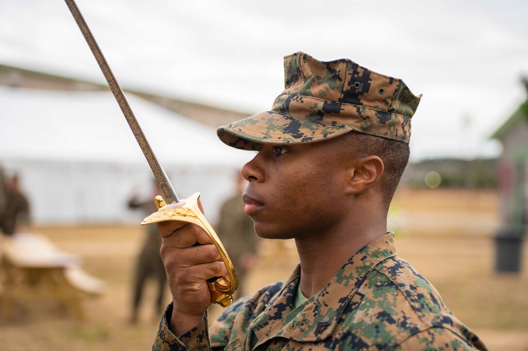 A Marine holds a sword close to his face.