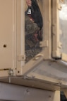 A soldier sits inside a simulated humvee standing on its side