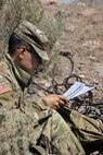 A soldier writes down notes and coordinates as he listens to a low level audio interceptor