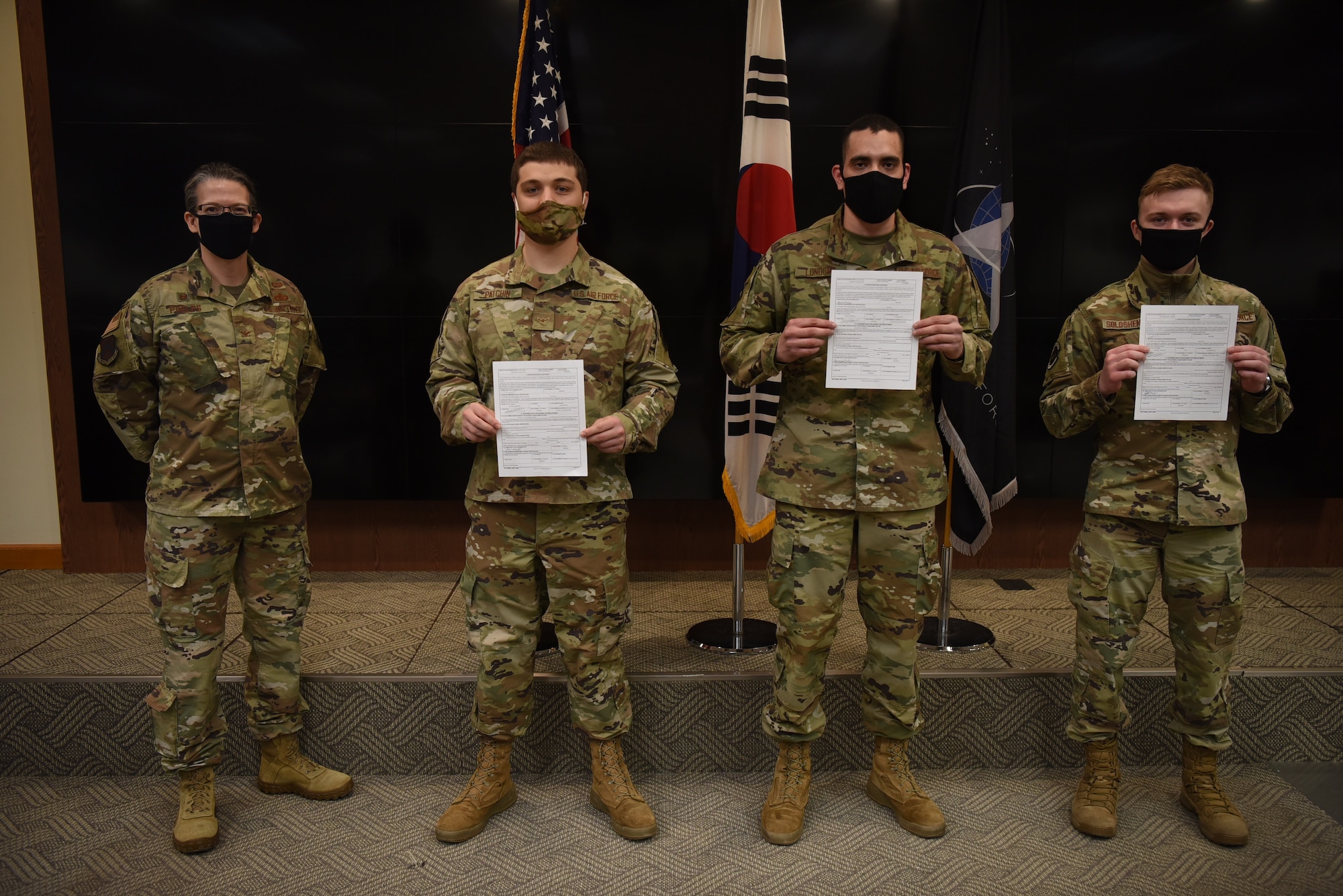 Colonel Jennifer Phelps stands with Airman 1st Class Anton Soloshenko, Airman 1st Class Emmanuel Londono, and Airman Nickolai Patchin as they show their signed Form 4, transferring them to the U.S. Space Force, at Kunsan Air Base, Republic of Korea Feb. 1, 2021.