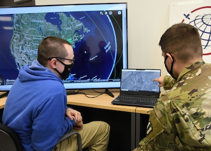 Clyde Stanfield, vice president of radar processes, Orbital Effects, and U.S. Army Sgt. Joshua McKee, fire control noncommissioned officer, 1st Battalion, 182nd Field Artillery Regiment, Michigan Army National Guard, work in the Orbital Effects office during Northern Strike/”Winter Strike 21” at Camp Grayling Maneuver Training Center, Michigan Jan. 28, 2021. Orbital Effects used satellites during the exercise to assist troops on the ground with targeting and mission planning.