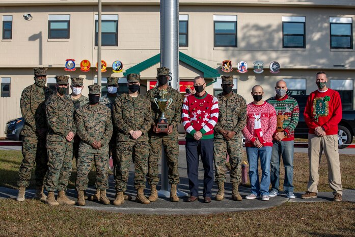 U.S. Marines belonging to Marine Wing Support Squadron 272 pose for a photo with the Commander’s Cup at the Marine Aircraft Group 26 headquarters building on Marine Corps Air Station New River, Dec. 18, 2020. Units competed in a series of different sporting events and tournaments, each winning unit was awarded with a Commanders’ Cup trophy and monetary compensation in the form of unit and Family Readiness funds. (U.S. Marine Corps Photo by Lance Cpl. Isaiah Gomez)