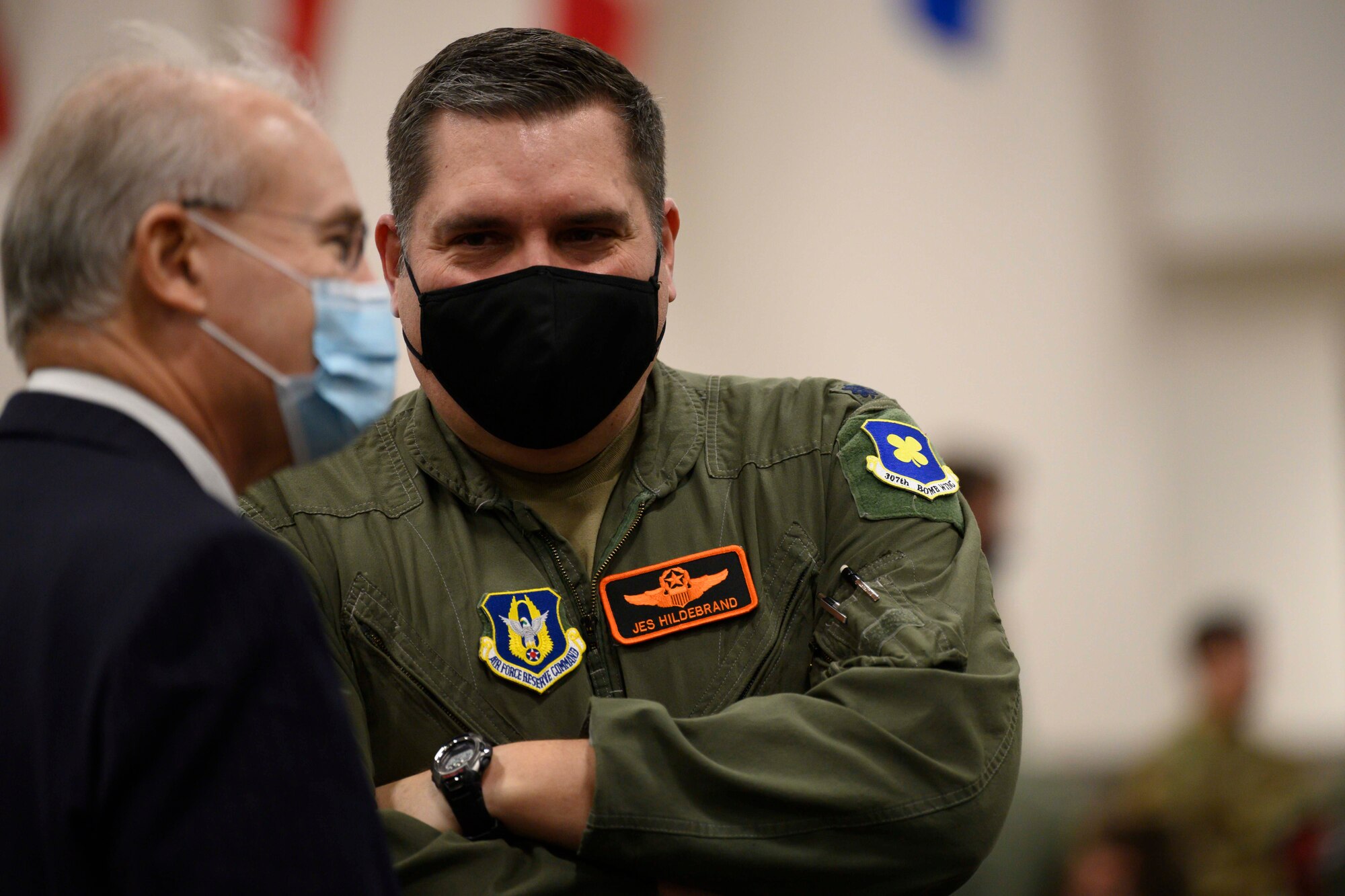 Close up photo of two men speaking while wearing masks.