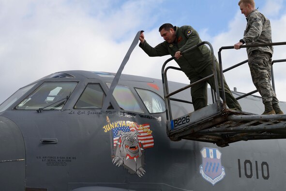 Photo of two Airmen pulling tape off name plate of a B-52