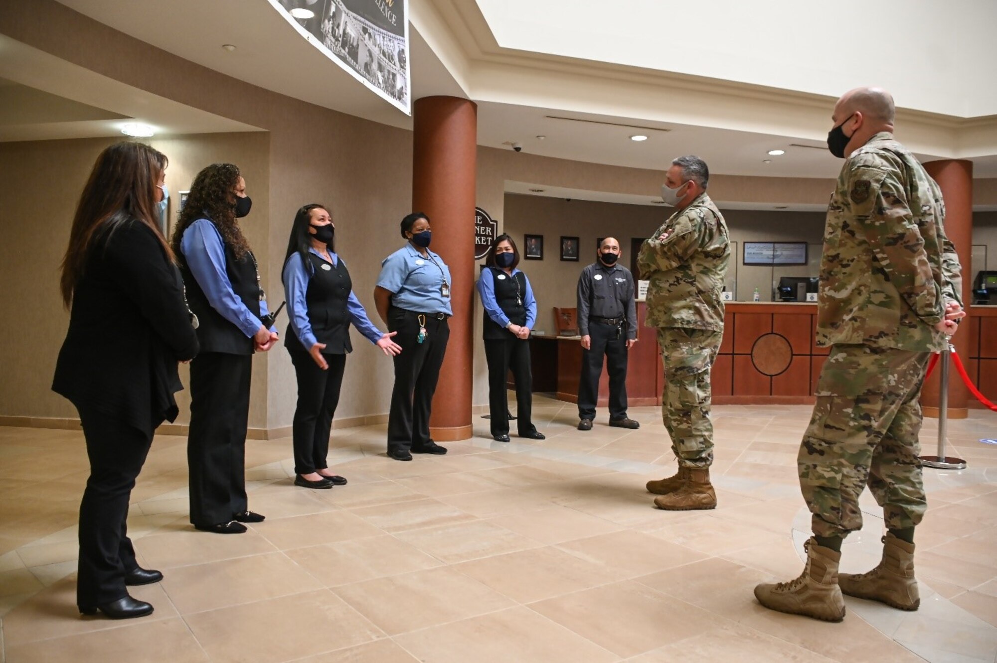 Hotel workers face two men in military uniforms in a circle