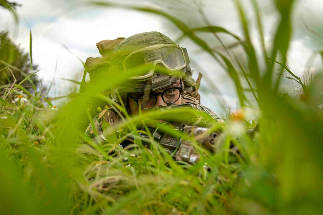 A Marine is partially hidden behind green grass.