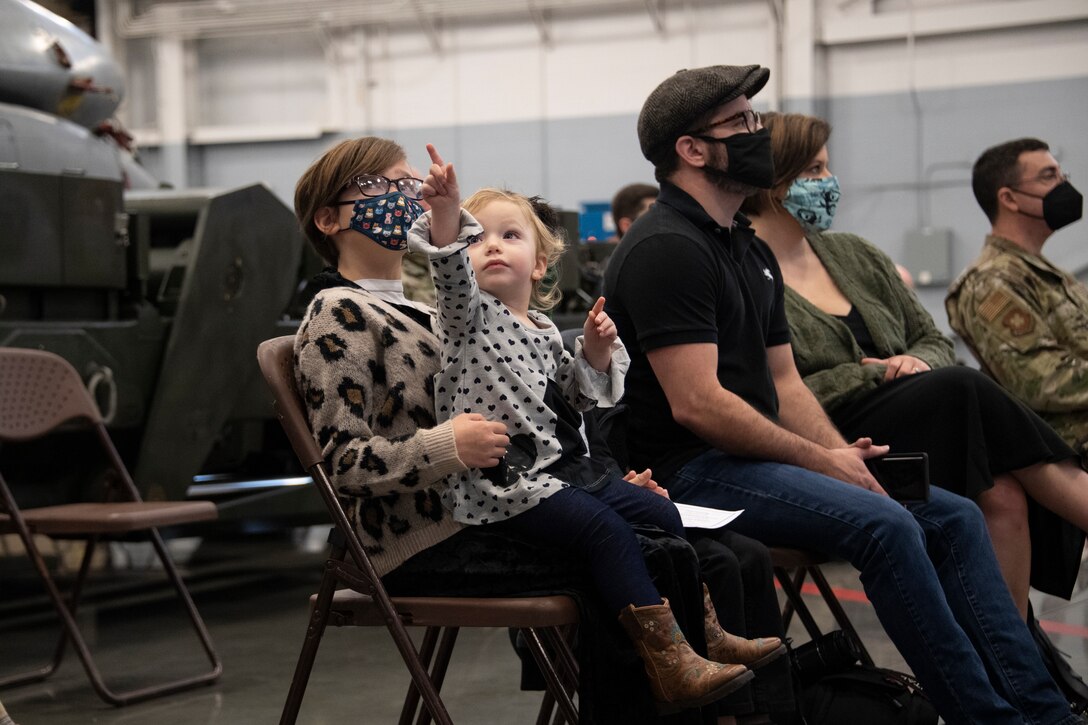 Photo of child sitting in young girls lap.  The child points to something off the screen.