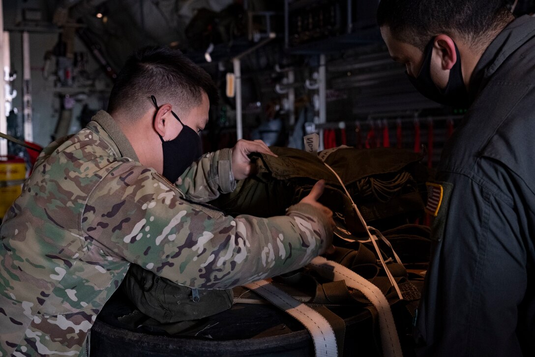 Staff Sgt. Jay Tuazon, left, and Tech. Sgt. Brian Gates, 36th Airlift Squadron loadmasters, check a container delivery system bundle at Yokota Air Base, Japan, Jan. 22, 2021.