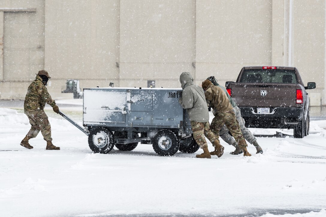 Maintainers from the 436th Aircraft Maintenance Squadron, push ground equipment through the snow at Dover Air Force Base, Delaware, Jan. 31, 2021. Despite a prolonged nor’easter, the base maintained normal operations and prepared for additional snowfall. (U.S. Air Force photo by Roland Balik)