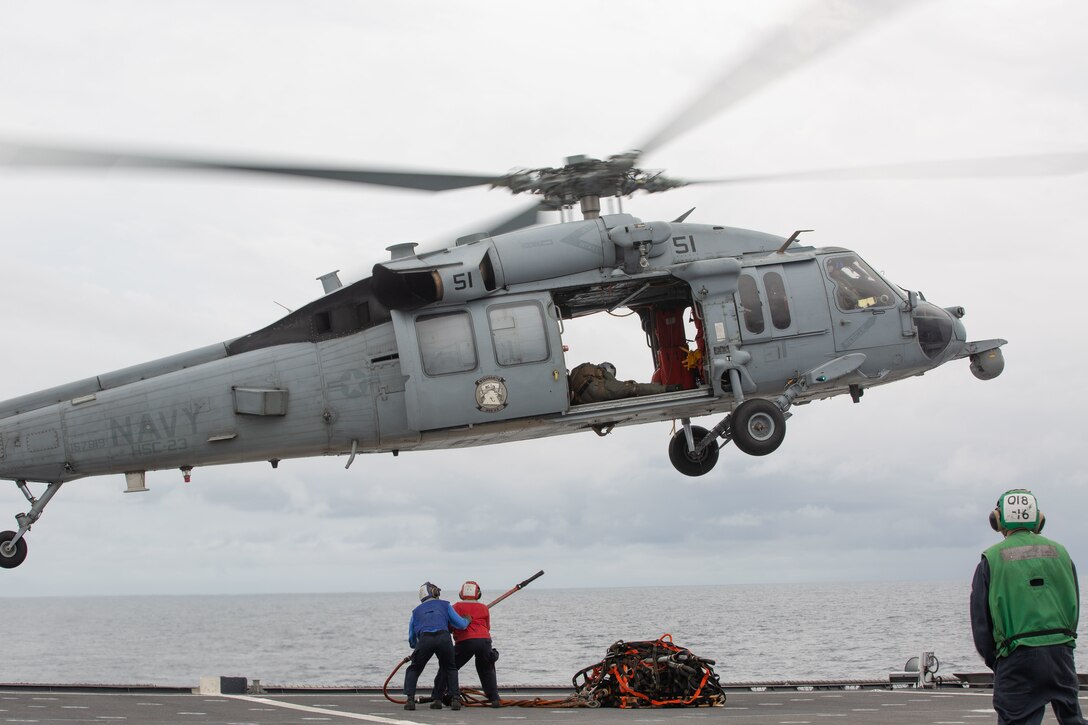 EASTERN PACIFIC OCEAN – Culinary Specialist Seaman Kobe Norfleet and Culinary Specialist 2nd Class Simone Jones, both with the Independence-class littoral combat ship USS Gabrielle Giffords (LCS 10), attach a hook to an MH-60S Sea Hawk during a vertical replenishment on the flight deck of the Gabrielle Giffords Nov. 25, 2020.