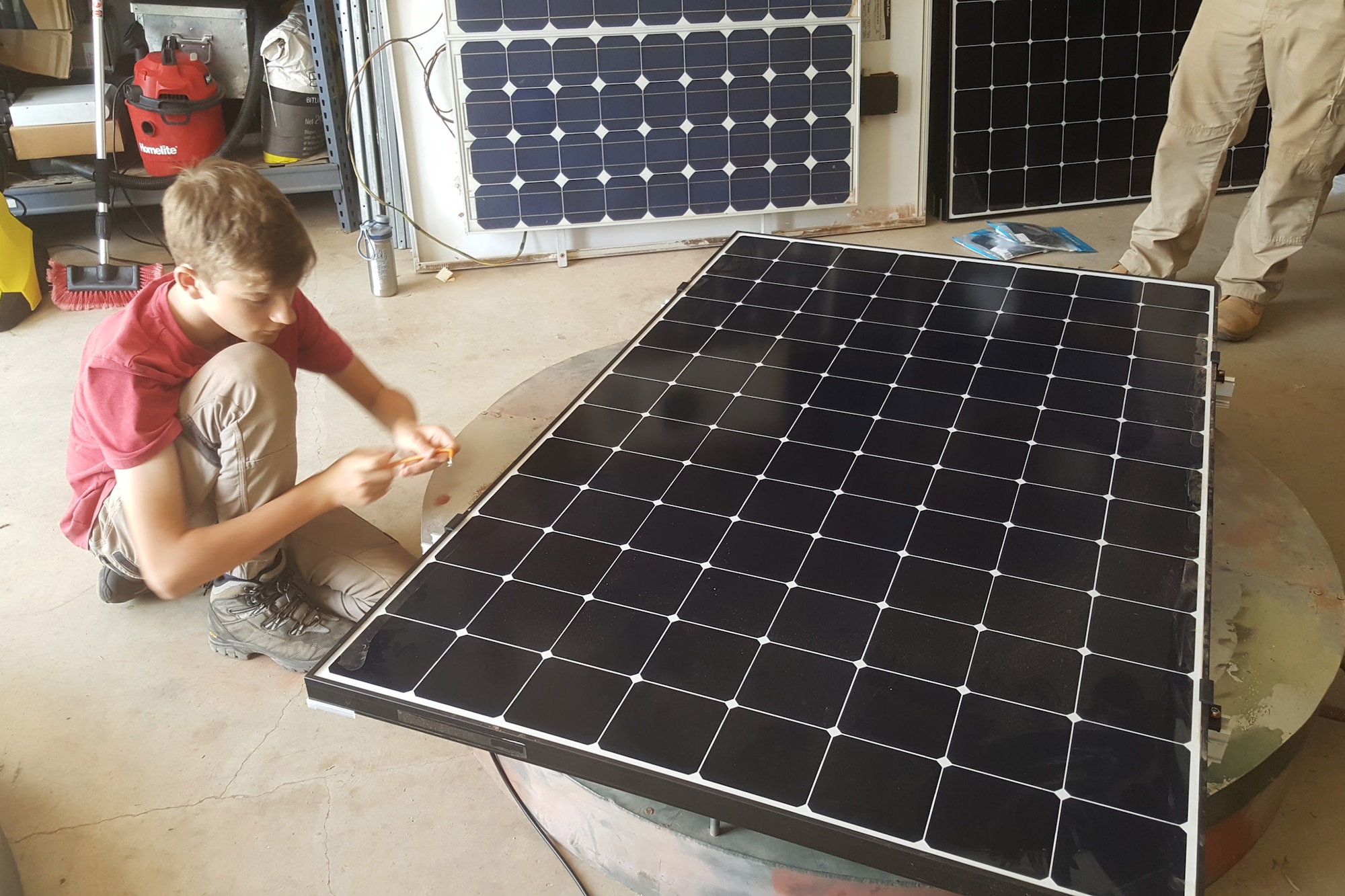 High school sophomore Paxton Rhoads uses security bolts to fasten a solar panel to a power box lid to deter possible theft in the austere Australian Outback.  Rhoads immersed with Airmen from the 709th Technical Maintenance Squadron's Detachment 421 in Alice Springs, Australia as part of a school community outreach project.  (U.S. Air Force courtesy photo)