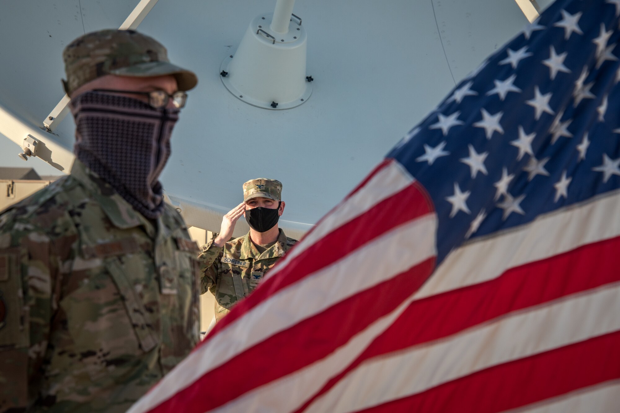 A guardian salutes the flag as a man sings the national anthem