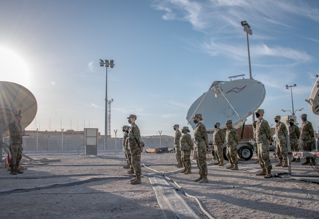 airmen stand in a row listening to a man speak