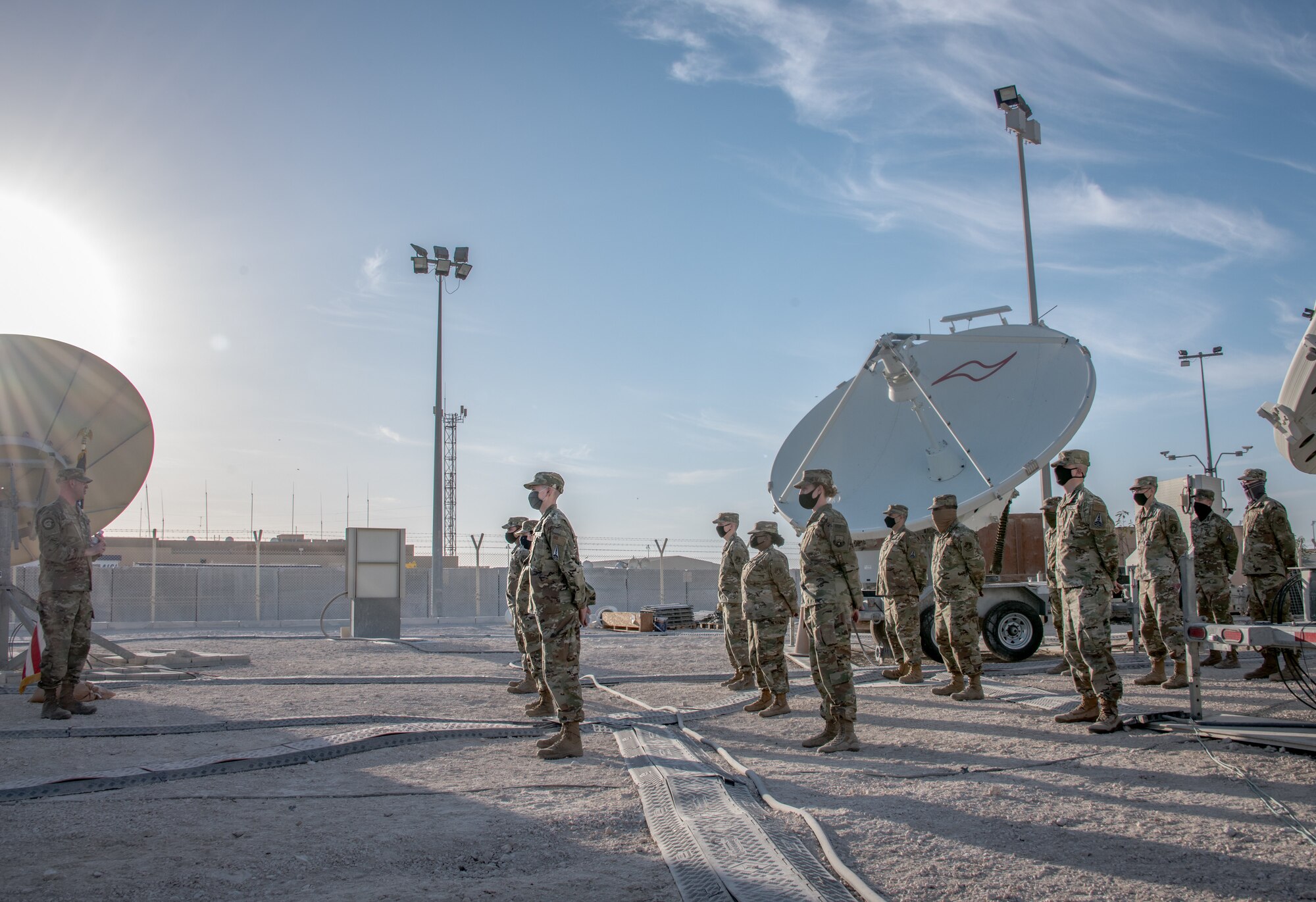 airmen stand in a row listening to a man speak