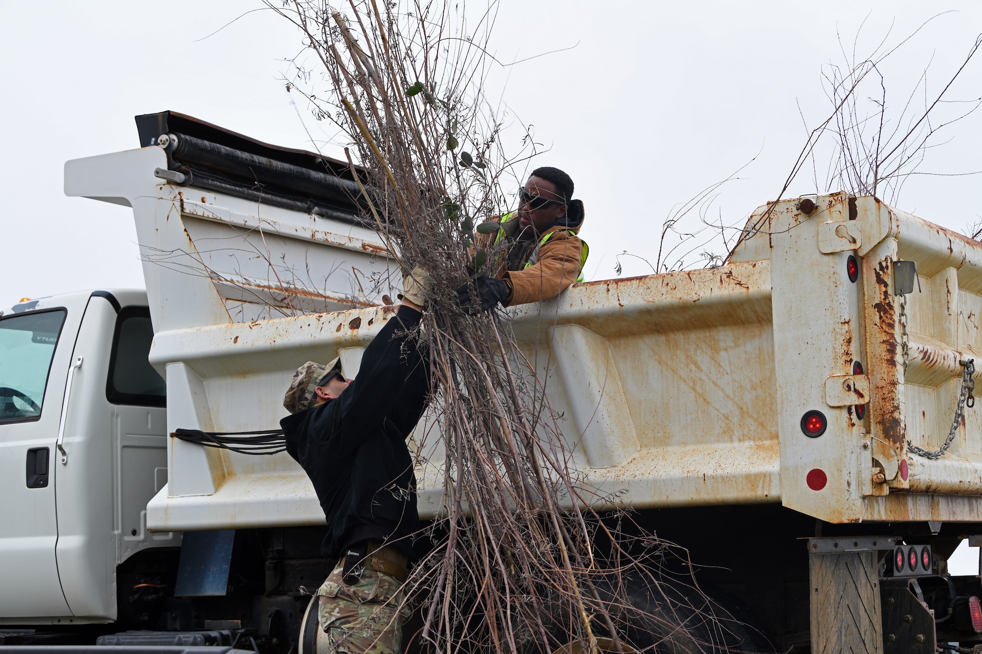 Staff Sgt. Daniel Eaton, left, and Senior Airman Diante Townsend, 9th Civil Engineering Squadron pavement and construction equipment specialists, loads a dump truck with young trees that were growing in a ditch, Jan. 8, 2020, at Beale Air Force Base, California. The trees were cut down as a flood prevention effort. (U.S. Air Force photo by Airman 1st Class Luis A. Ruiz-Vazquez)
