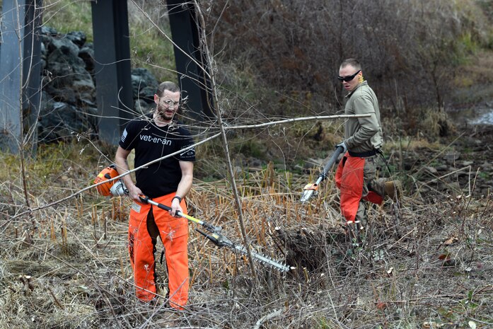 Nick Sobola, left, and Airman 1st Class Jonathan Evett, 9th Civil Engineering Squadron pavement and construction equipment specialists, cut down young trees growing in a ditch, Jan. 8, 2020, at Beale Air Force Base, California. The trees were cut down as a flood prevention effort. (U.S. Air Force photo by Airman 1st Class Luis A. Ruiz-Vazquez)