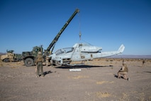 Marines providing security while lifting aircraft with model crane so that it can be repaired.