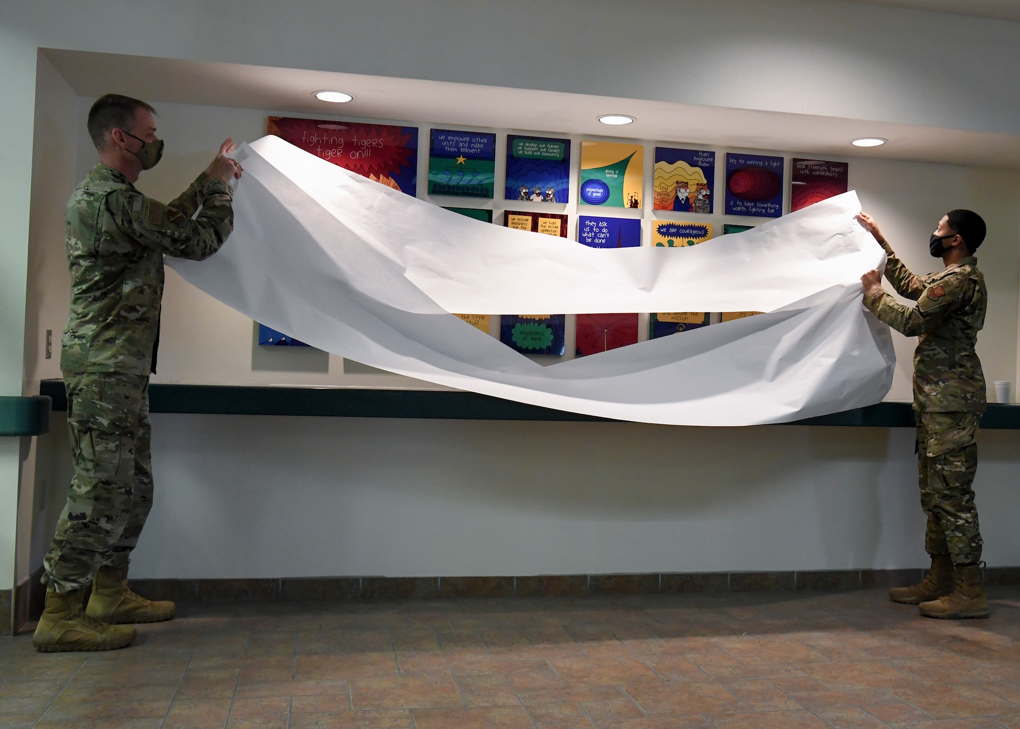 two military members removing the covering from a display